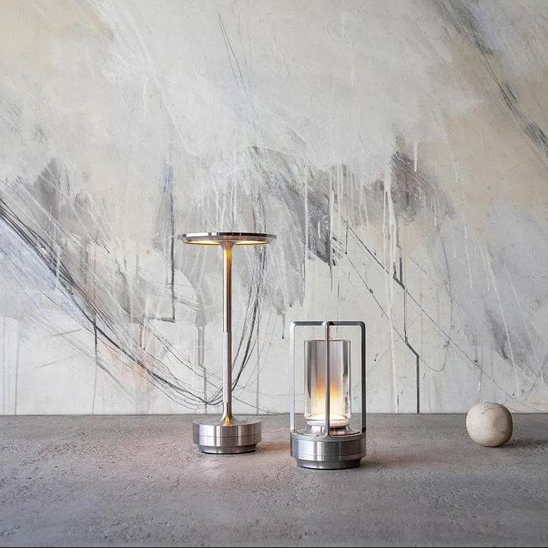 Two modern table lamps on a concrete surface with abstract art in the background
